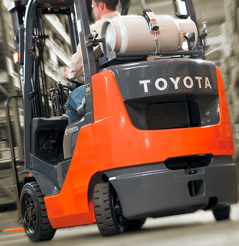A Toyota forklift operator taking advantage of the vehicle's rear steering to easily maneuver in a tight space